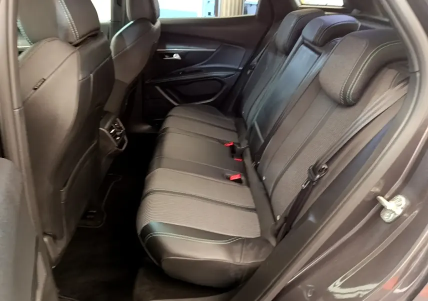 Vue côté droit de la banquette arrière en tissu et cuir noir du Peugeot 3008 gris foncé, avec ceintures et appuie-têtes visibles.