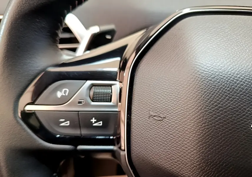 Gros plan sur les commandes gauche du volant cuir du Peugeot 3008 gris foncé, version BlueHDi 130 Allure 2022.