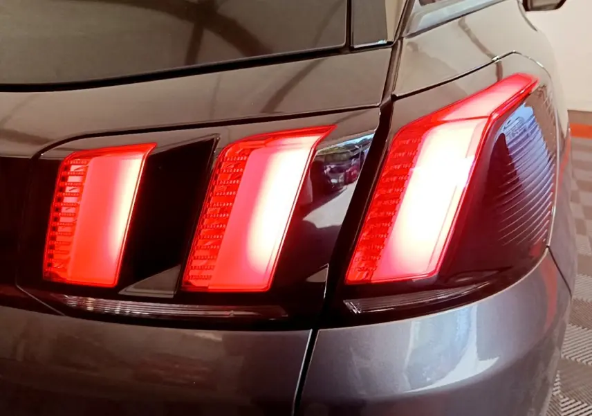 Gros plan sur le feu arrière droit rouge du Peugeot 3008 gris foncé, mettant en valeur son design en trois griffes.