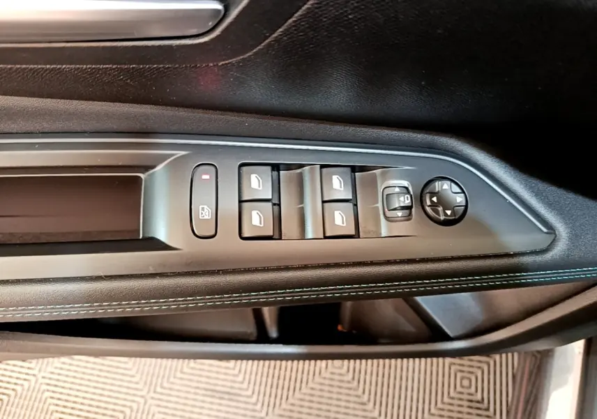 Vue rapprochée du panneau de commandes des vitres et rétroviseurs côté conducteur du Peugeot 3008 gris foncé 2022.
