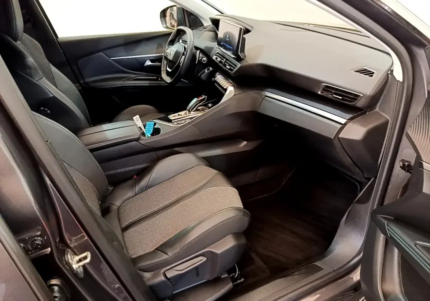 Vue intérieure côté conducteur du Peugeot 3008 gris foncé, avec tableau de bord moderne et écran tactile central.