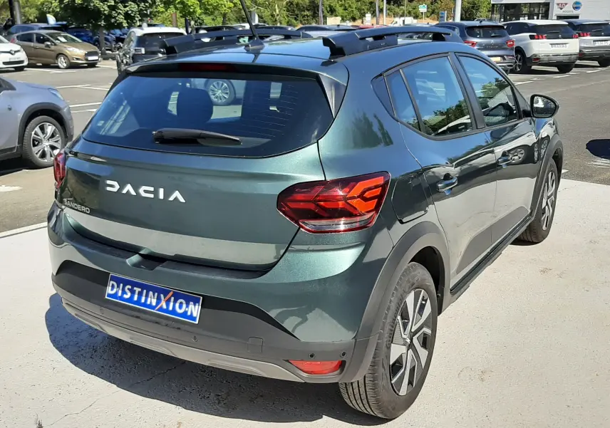 Vue 3/4 arrière droite d'une Dacia Sandero Stepway 2025 vert cèdre avec feux arrière LED et toit noir.