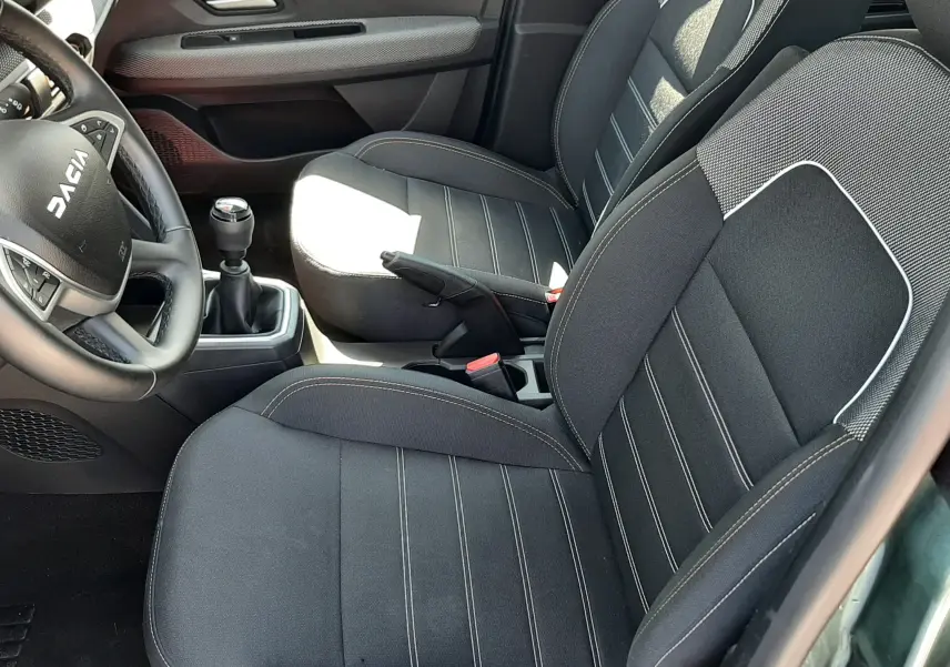 Vue intérieure côté conducteur de la Dacia Sandero Stepway 2025, sièges tissu gris avec coutures contrastées.