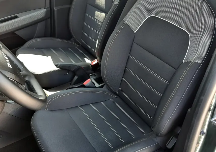 Vue intérieure côté conducteur de la Dacia Sandero Stepway 2025, sièges tissu gris foncé avec surpiqûres claires.