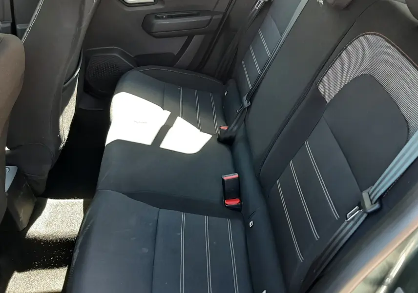Vue intérieure côté arrière droit de la banquette tissu gris foncé avec surpiqûres blanches de la Dacia Sandero Stepway 2025.