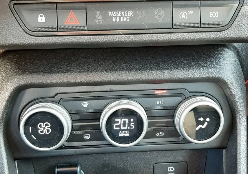 Gros plan sur la console centrale noire de la Dacia Sandero Stepway avec commandes de climatisation et boutons de sécurité.