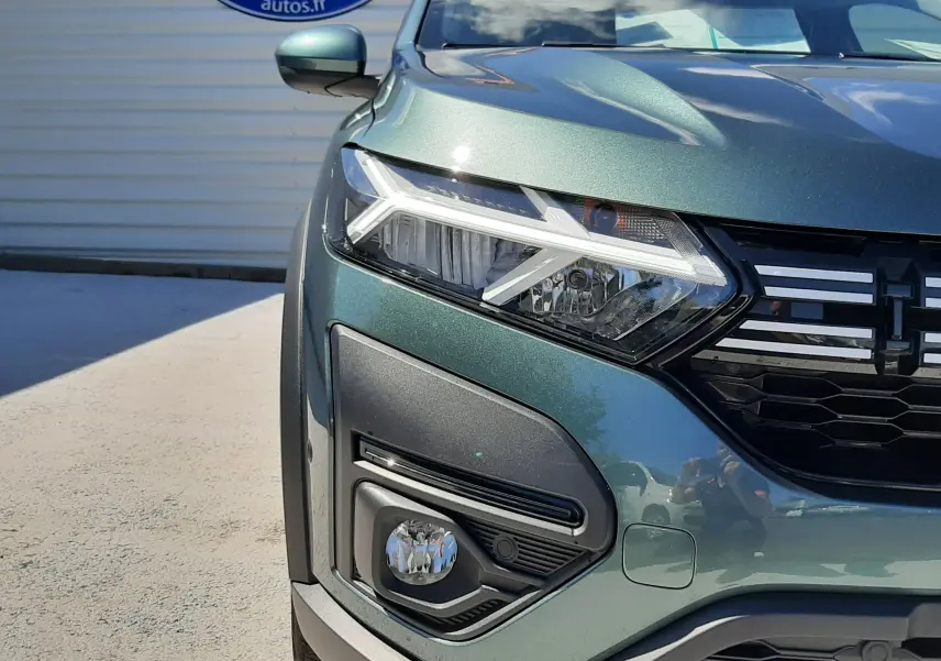 Vue avant gauche rapprochée d'une Dacia Sandero Stepway 2025 en vert cèdre avec phares LED et calandre noire.
