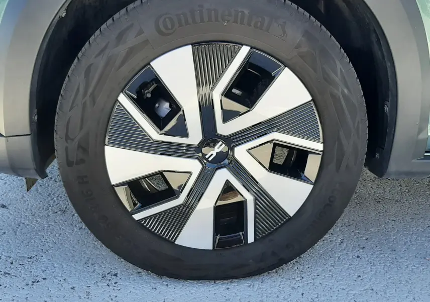Gros plan sur la roue avant droite d'une Dacia Sandero Stepway 2025 vert cèdre avec jante au design moderne bicolore.