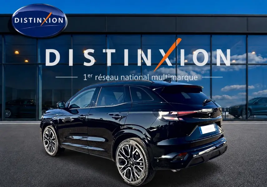 Vue 3/4 arrière d'un Renault Austral noir brillant avec jantes alliage et toit surélevé devant un showroom Distinxion.