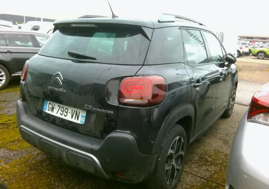 Vue 3/4 arrière droite d'un Citroën C3 Aircross noir avec jantes alliage diamantées et barres de toit noires.