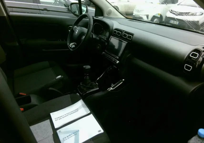 Vue intérieure côté conducteur du Citroën C3 Aircross 2024, tableau de bord noir avec écran tactile central.