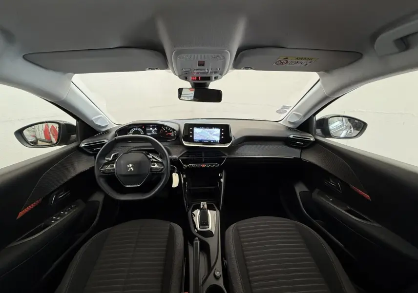 Intérieur noir de la Peugeot 208 2021, vue frontale du tableau de bord avec écran tactile et volant multifonctions.