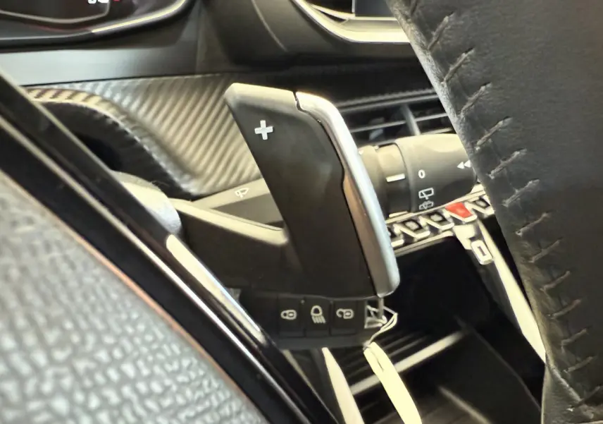 Gros plan sur la palette de changement de vitesse droite et le volant cuir noir de la Peugeot 208 PureTech 100.