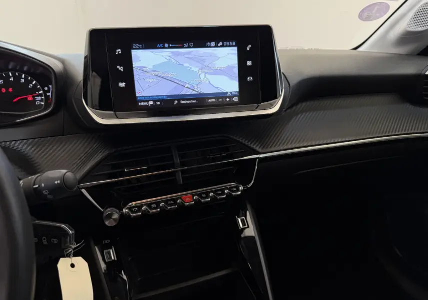 Vue intérieure du tableau de bord de la Peugeot 208 noire, avec écran tactile de navigation et finition carbone.