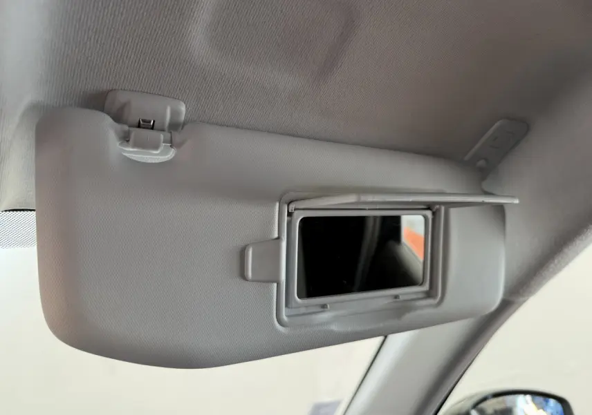 Miroir de courtoisie ouvert sur le pare-soleil côté conducteur d'une Peugeot 208 noire, vue intérieure rapprochée.