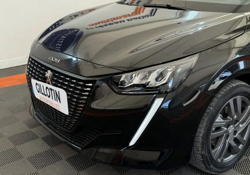 Vue 3/4 avant droit d'une Peugeot 208 noire mettant en valeur sa calandre distinctive et ses phares LED effilés.