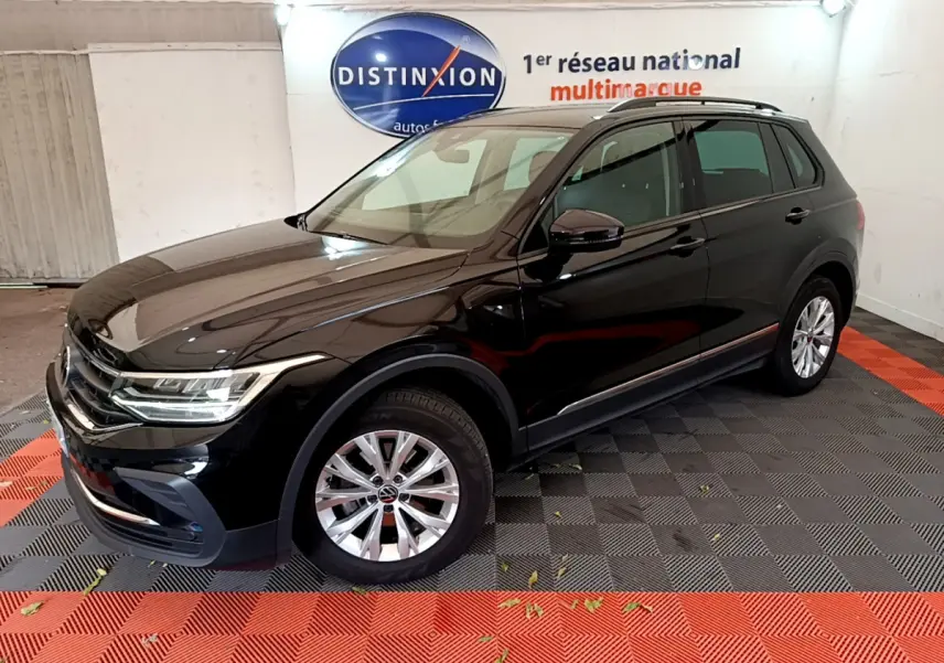 Volkswagen Tiguan noir vu en 3/4 avant droit dans un showroom avec jantes argentées et toit noir.