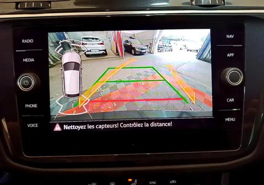 Écran tactile intérieur du Volkswagen Tiguan noir montrant la caméra de recul avec guidage de trajectoire coloré.