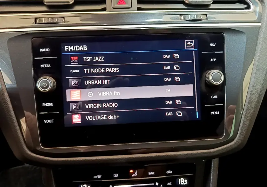 Écran tactile central du Volkswagen Tiguan noir 2021 affichant les stations radio FM/DAB dans l'habitacle.