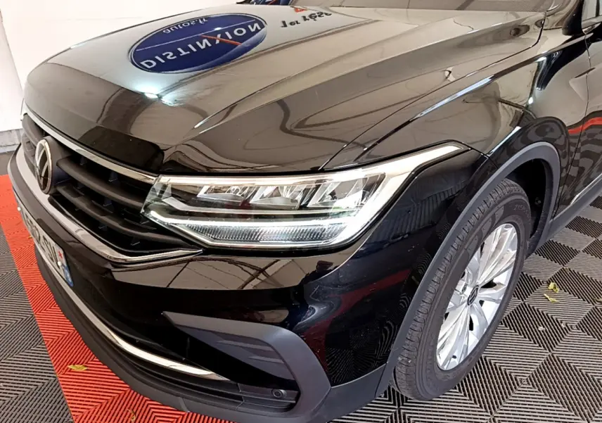Vue 3/4 avant droit du Volkswagen Tiguan noir 2021 avec phares LED et jantes alliage visibles.