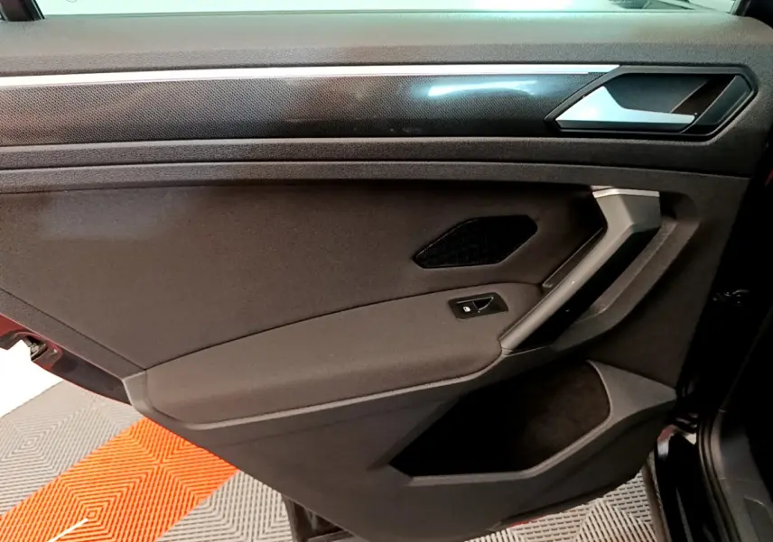 Vue intérieure de la porte arrière droite noire du Volkswagen Tiguan 2021 avec poignée argentée et commande de vitre électrique.