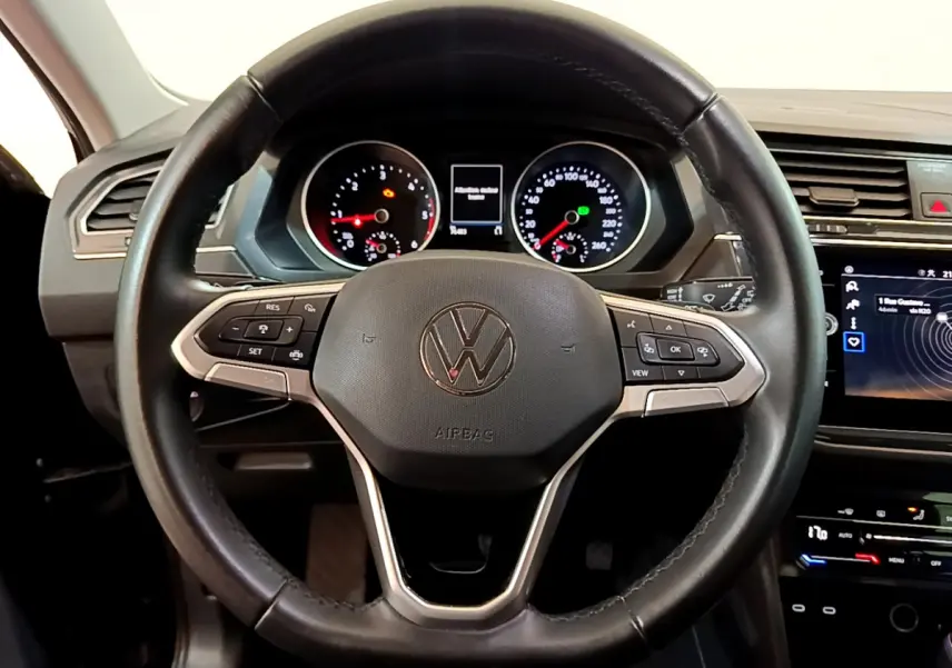Vue rapprochée du volant cuir noir du Volkswagen Tiguan 2021 avec tableau de bord et écran tactile visibles.
