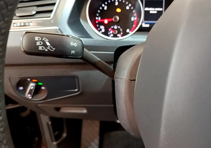 Gros plan sur la manette de clignotant à gauche du volant dans l'habitacle noir du Volkswagen Tiguan 2021.