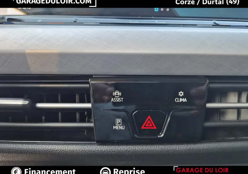 Gros plan sur la console centrale noire avec boutons d'assistance, climatisation et alerte de danger de la Volkswagen Golf bleue 2023.