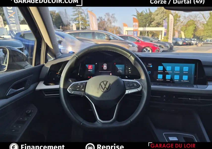 Vue intérieure centrée sur le volant cuir noir et le tableau de bord numérique de la Volkswagen Golf bleue 2023.