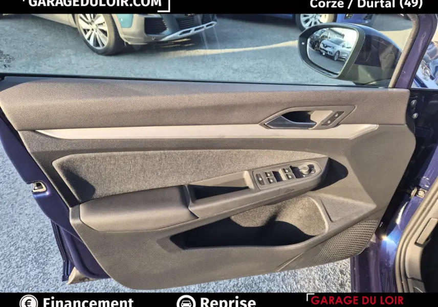 Vue intérieure de la porte avant gauche bleu foncé de la Volkswagen Golf 2023 avec commandes électriques et garniture tissu et cuir.