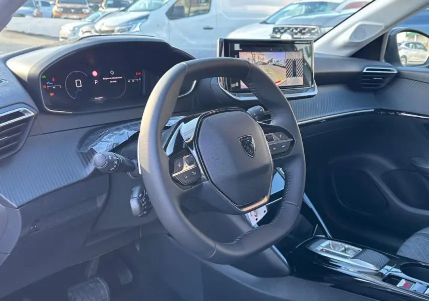 Vue intérieure côté conducteur du Peugeot 208 Hybrid blanc, avec volant multifonction et écran tactile central.