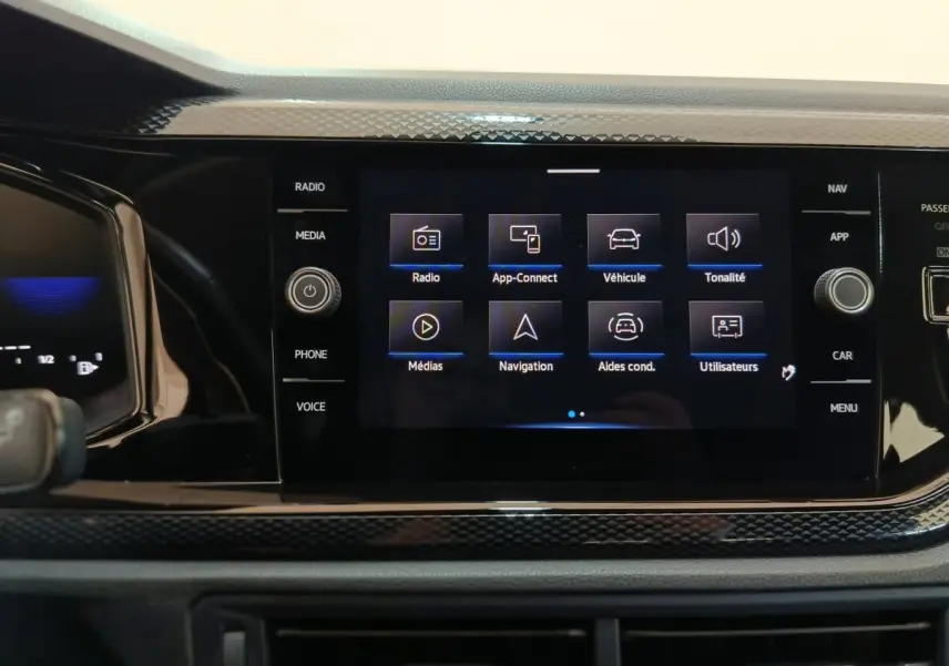 Écran tactile central allumé du Volkswagen Taigo gris foncé, affichant le menu principal multimédia et navigation.