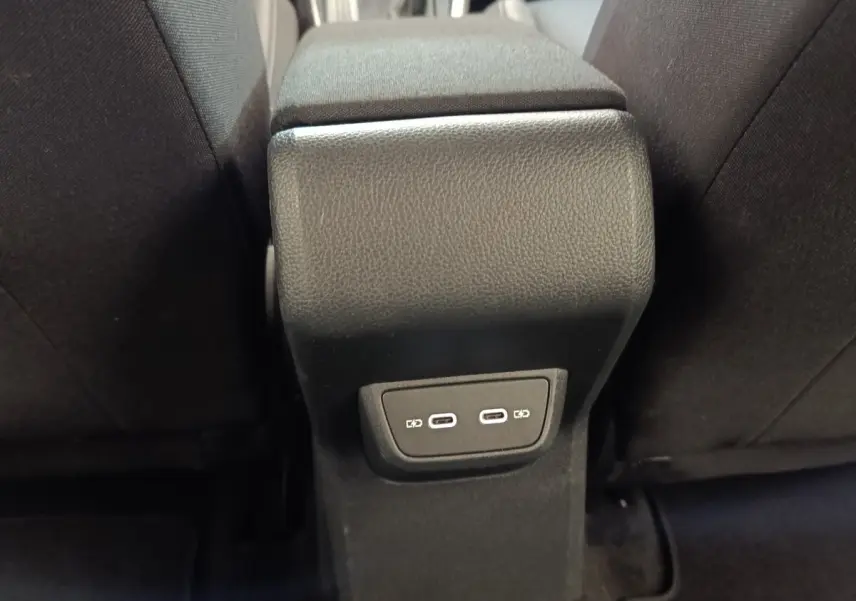Vue rapprochée de la console centrale arrière noire avec deux ports USB-C entre les sièges avant noirs.