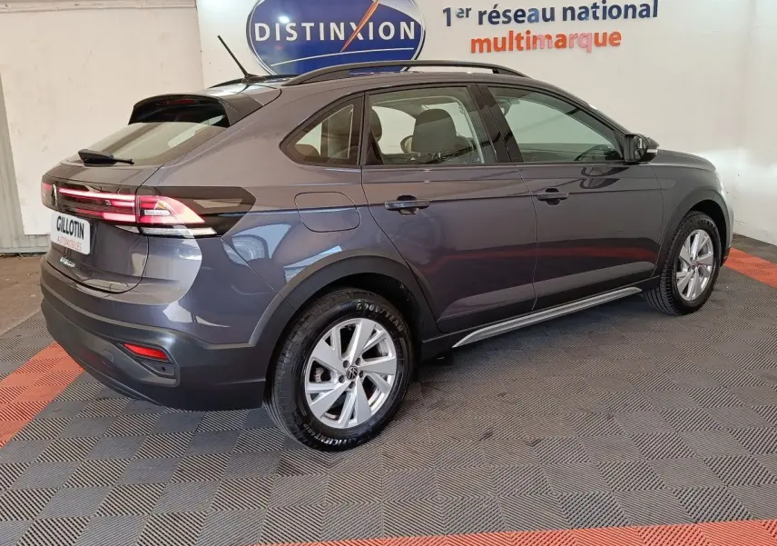 Vue 3/4 arrière droit d’un Volkswagen Taigo gris foncé 2023 avec feux arrière allumés et jantes alliage.