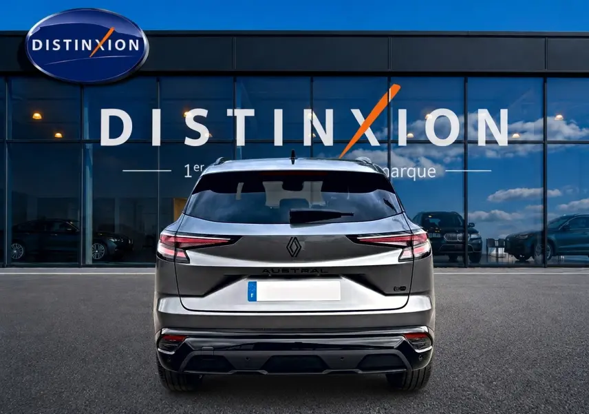 Vue arrière d'un Renault Austral gris schiste garé devant une vitrine avec logo Distinxion en arrière-plan.