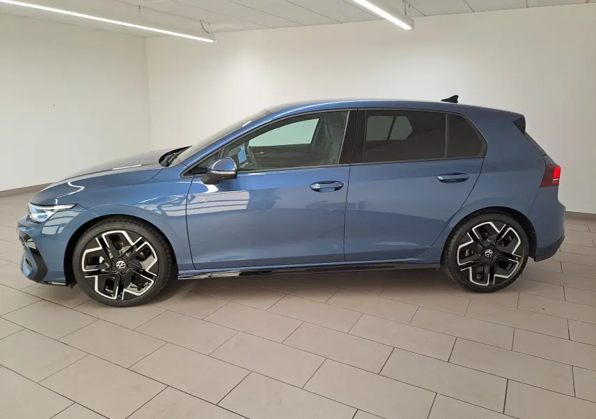 Vue latérale gauche d'une Volkswagen Golf 1.5 eTSI R-Line 2025 en bleu anémone avec jantes alliage distinctives.