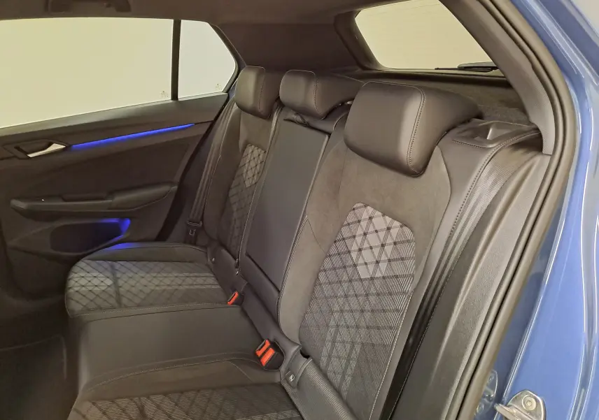 Vue intérieure côté droit des sièges arrière en tissu et alcantara avec éclairage d'ambiance bleu sur une Volkswagen Golf Bleu Anémone 2025.