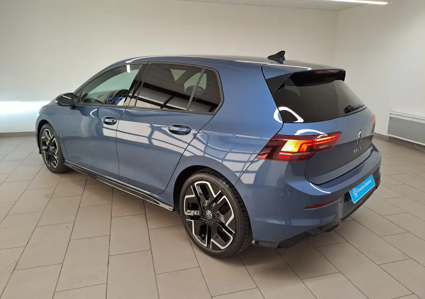 Volkswagen Golf 1.5 eTSI R-Line Bleu Anémone vue 3/4 arrière droit en intérieur avec jantes distinctives.