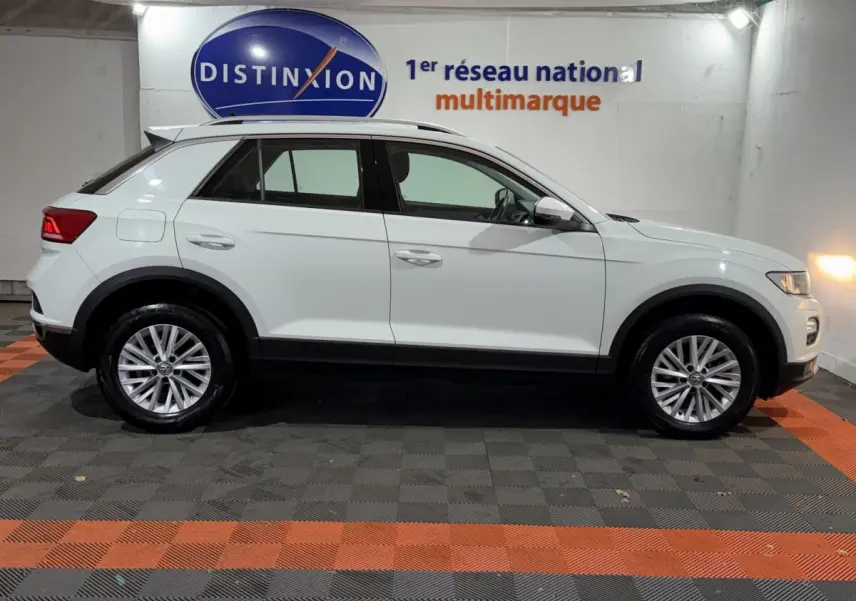 Profil côté gauche d'un Volkswagen T-Roc blanc 2020 garé en intérieur sur sol à damiers noir et orange.