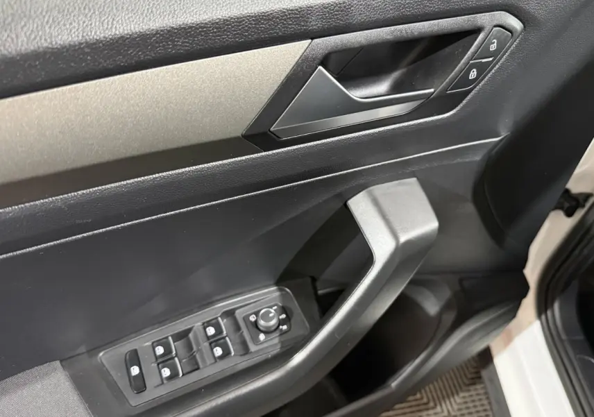 Gros plan sur la porte avant gauche blanche du Volkswagen T-Roc, montrant les commandes électriques et la poignée intérieure noire.