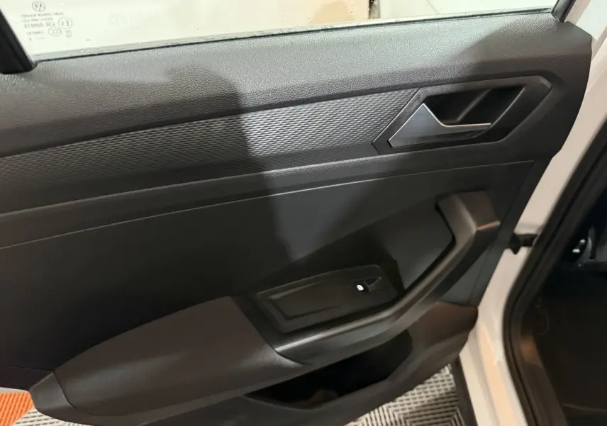 Intérieur côté gauche de la porte avant d'un Volkswagen T-Roc blanc, avec commande de lève-vitre et poignée noire.