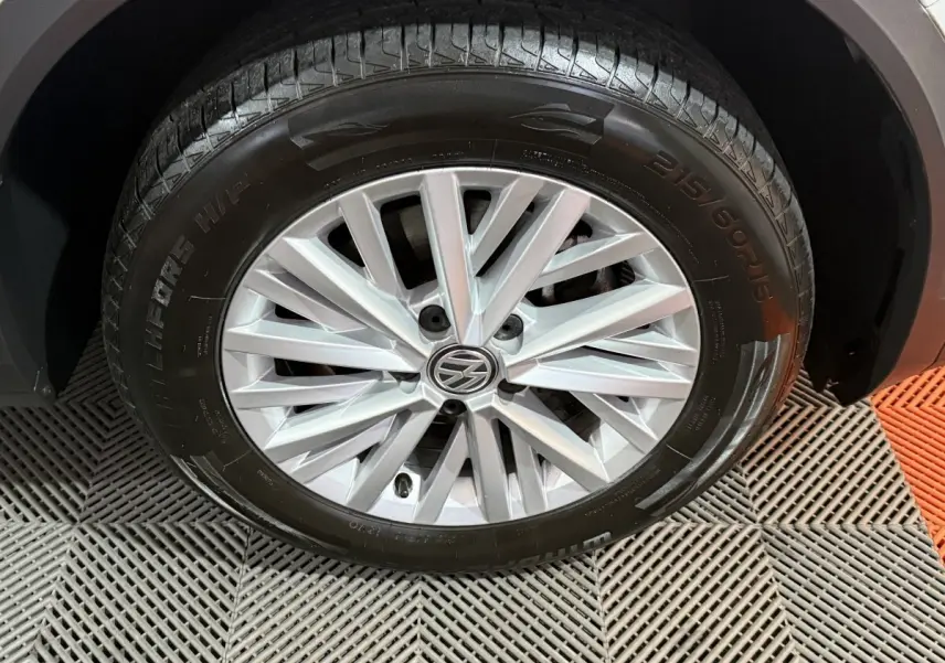 Gros plan sur la roue avant droite du Volkswagen T-Roc blanc, mettant en valeur la jante alliage à rayons fins.