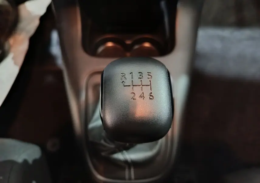 Gros plan sur le levier de vitesses manuel noir de la Citroën C3 BlueHDi 100 BVM PLUS 2024, intérieur sombre.