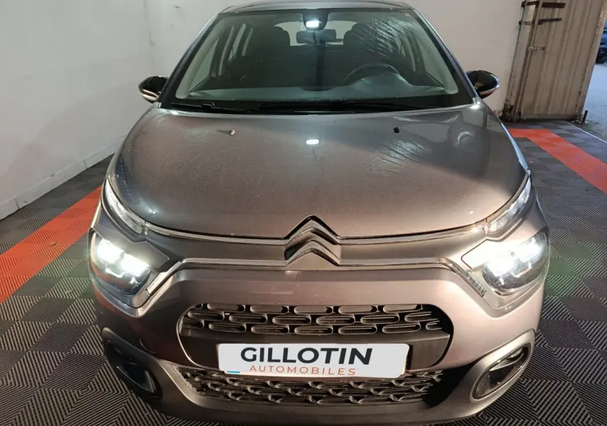 Vue avant d'une Citroën C3 gris foncé 2024 avec phares LED allumés dans un garage.