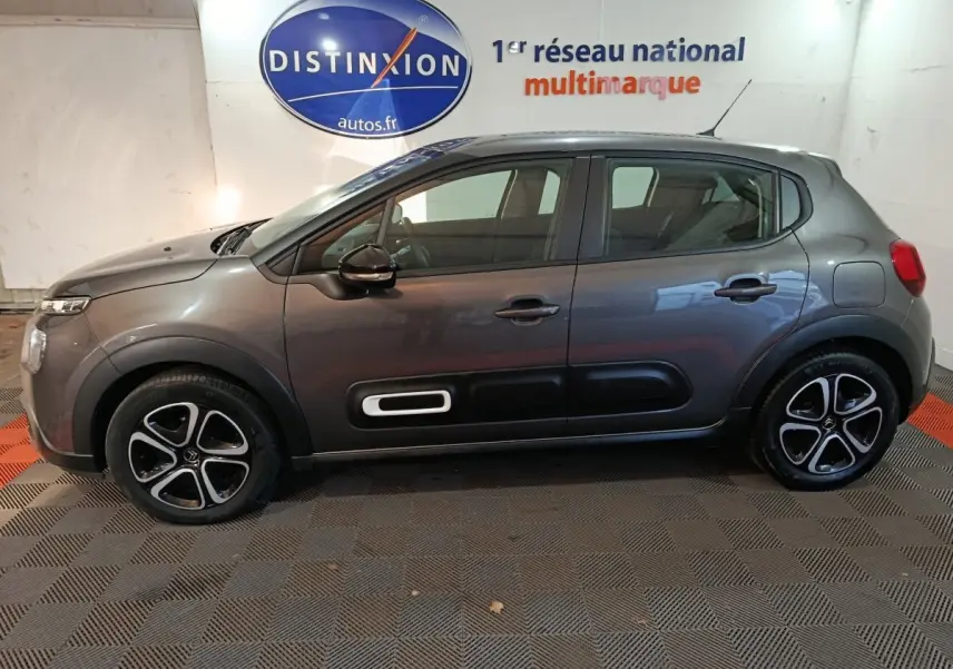 Vue de profil côté gauche d'une Citroën C3 gris foncé 2024 avec jantes alliage et protections latérales noires.