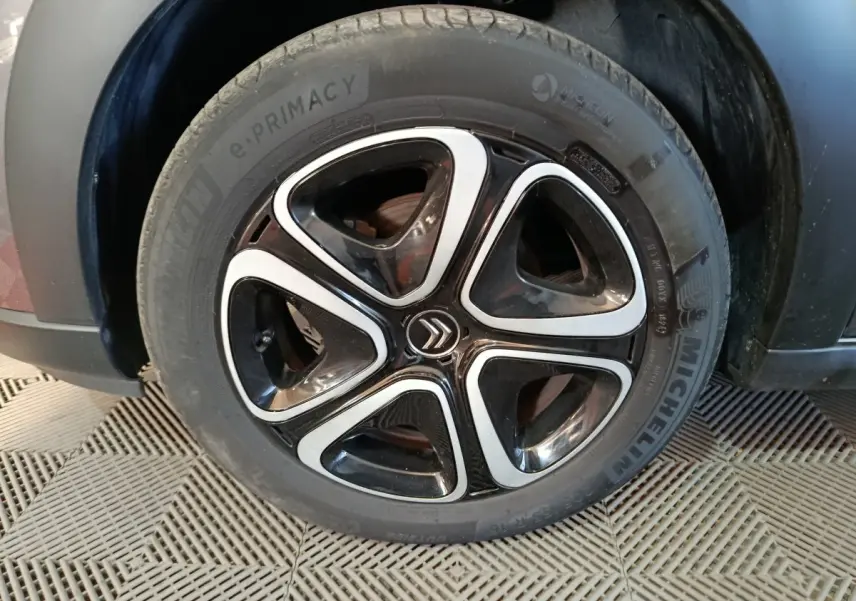 Gros plan sur la roue avant gauche d'une Citroën C3 gris foncé, avec jante alliage noire et argentée au design moderne.