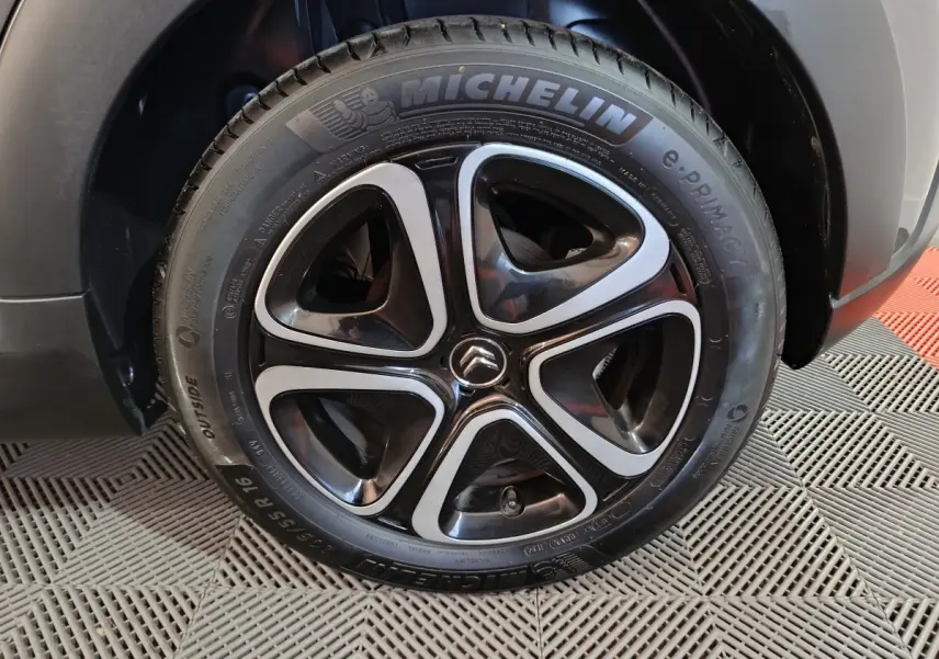 Gros plan sur la roue avant droite d'une Citroën C3 gris foncé, avec jante noire et argentée au design moderne.
