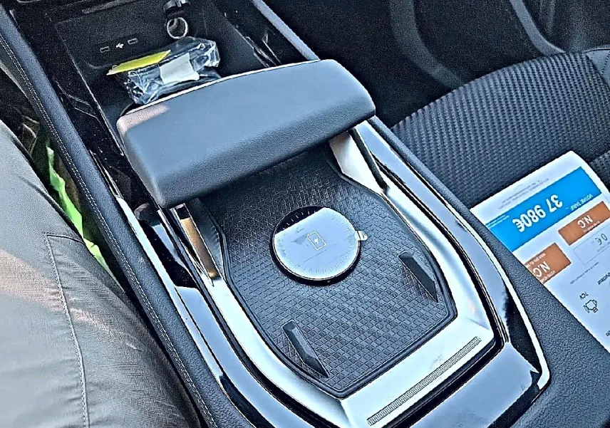 Gros plan sur l'accoudoir central noir et la console centrale du Renault Austral blanc nacré, intérieur tissu carbone alcantara.