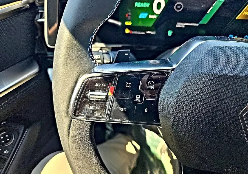 Gros plan sur le volant noir de la Renault Austral blanc nacre, avec commandes multifonctions visibles côté gauche.