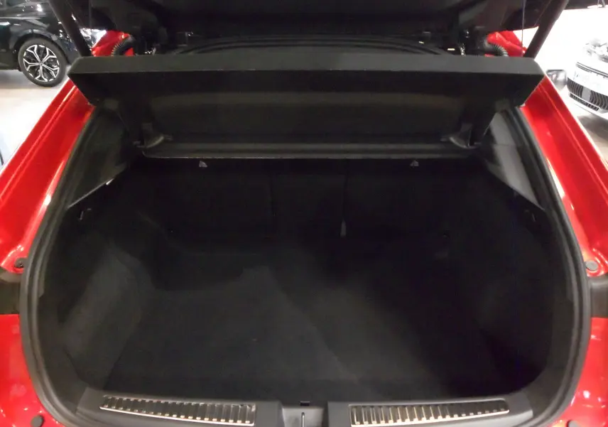 Coffre ouvert d'une Renault Rafale E-Tech Full Hybrid rouge flamme avec toit noir, vue arrière intérieure du coffre spacieux.